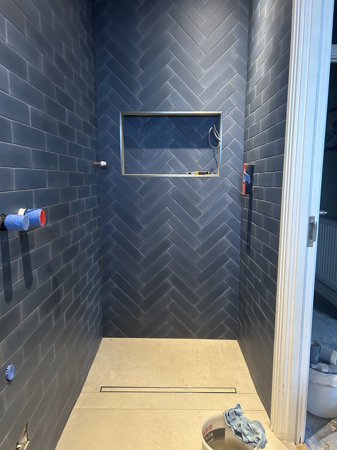 Deep blue bathroom walls tiled in a herringbone pattern
